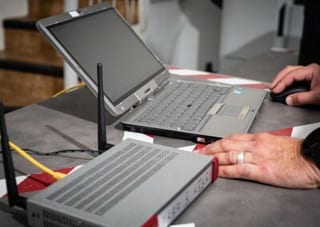 Un boîtier réseau à antennes en cours de configuration depuis un ordinateur portable posé à côté.